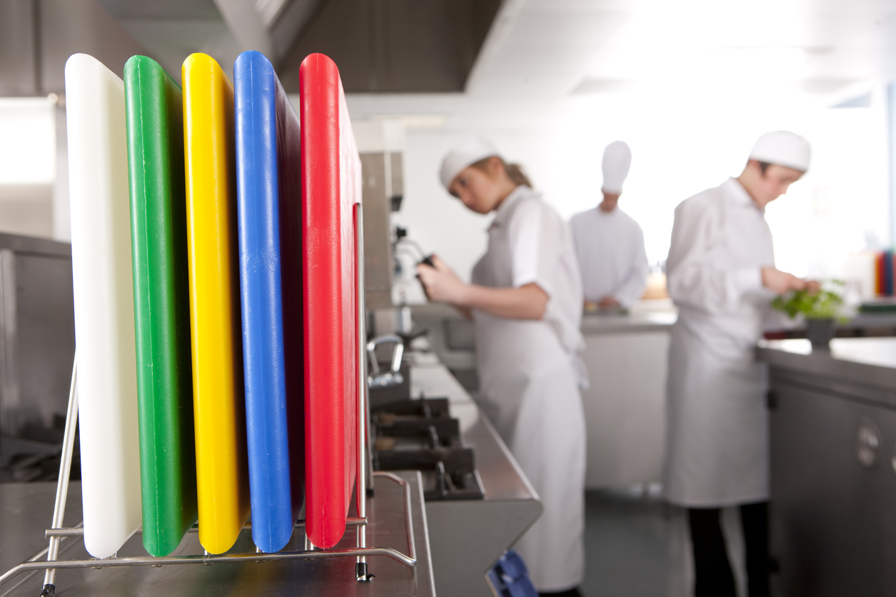 kitchen staff standing behind multi-coloured cutting boards in a restaurant