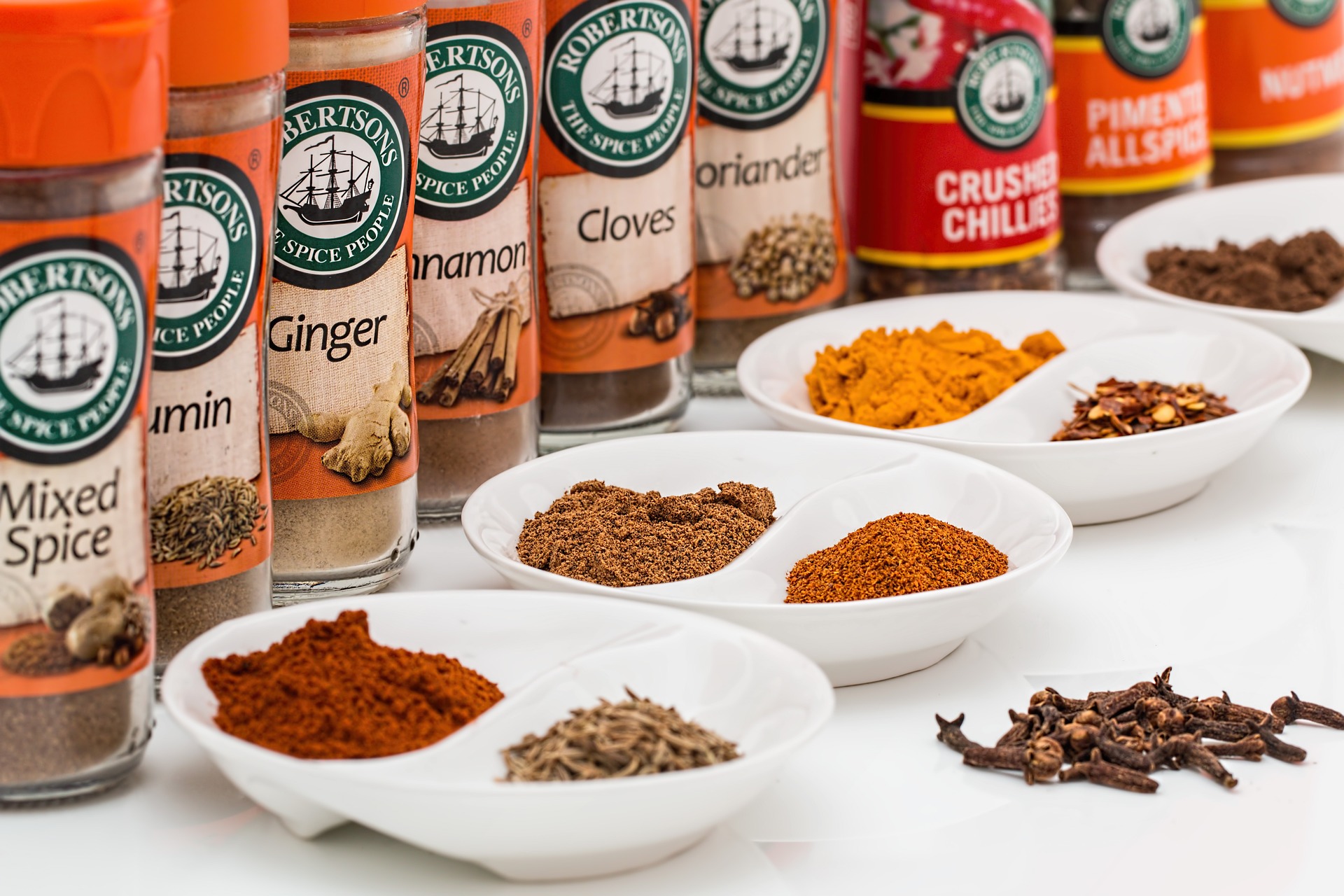 variety of dried herbs and spices in jars and small bowls