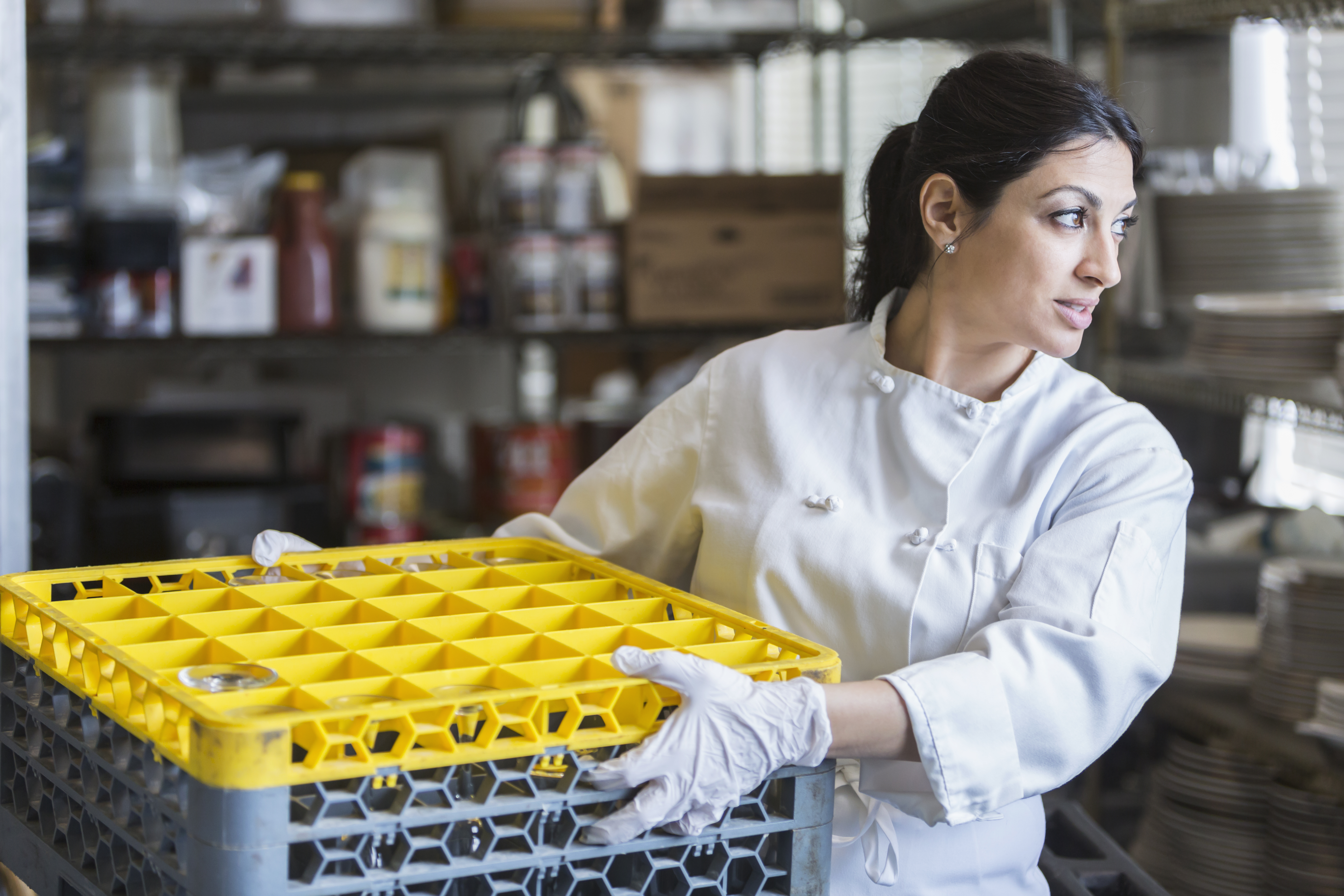 employee using a mechanical dishwasher in a restaurant