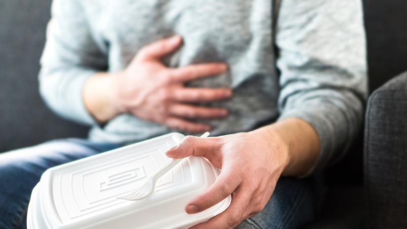 Person holding takeout container grasping stomach