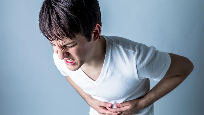 young boy bent over with severe abdominal pain from food poisoning