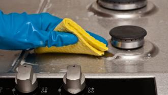 Food handler cleaning and sanitizing the surface of an oven