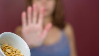 Girl saying no to bowl of peanuts