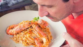 man smelling a seafood dish