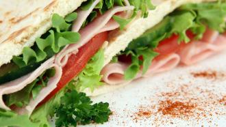 close up of a sandwich with lettuce, tomatoes and deli meat