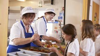 lunch ladies serving food to school children in a school cafeteria