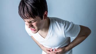 young boy clutching his stomach with abdominal pain