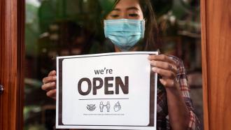 Woman hanging open sign on business door