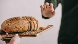 Individual refusing a slice of bread on a tray.